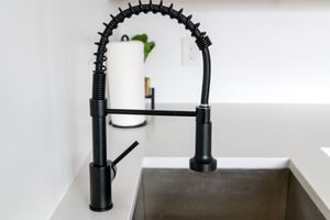 Sleek black faucet on white countertop in modern kitchen. Ideal for minimalist and contemporary designs.